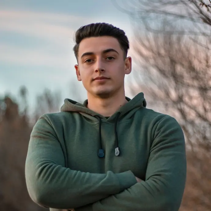man in green hoodie standing on blue metal railings during daytime