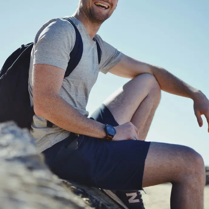 smiling man sitting on gray rock at daytime